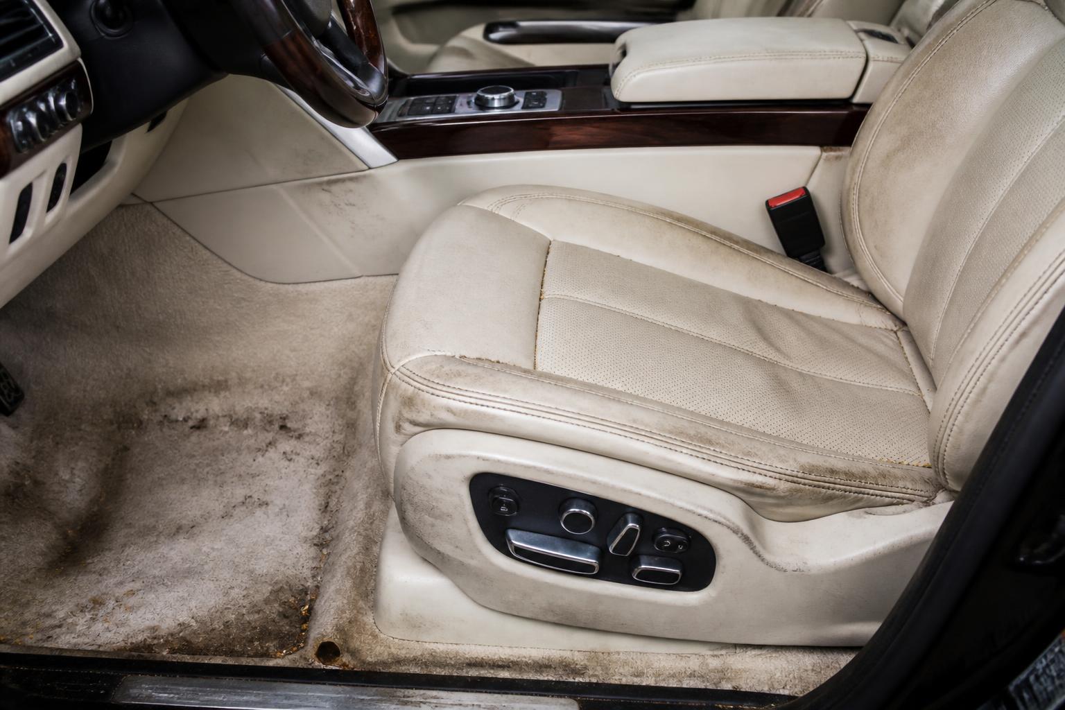 Dirty cream leather luxury car interior with stained carpet before restoration